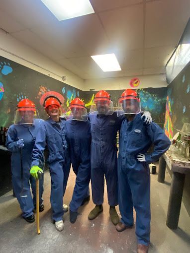 A group of people in blue jumpsuits and hard hats are posing for a picture.