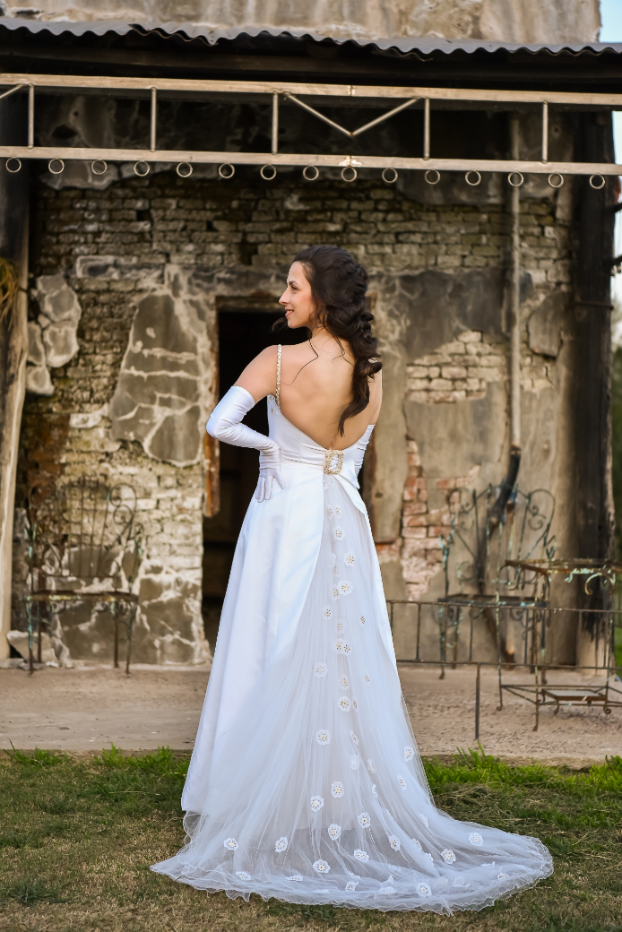 Una mujer con un vestido de novia está parada frente a un edificio de ladrillos.