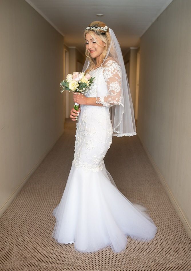 Una novia con un vestido de novia sostiene un ramo de flores en un pasillo.