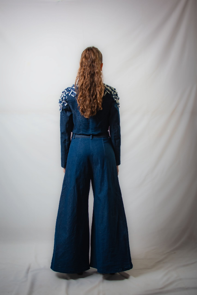 Una mujer lleva una chaqueta azul y pantalones anchos.