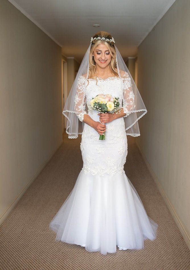Una novia con un vestido de novia sostiene un ramo de flores en un pasillo.