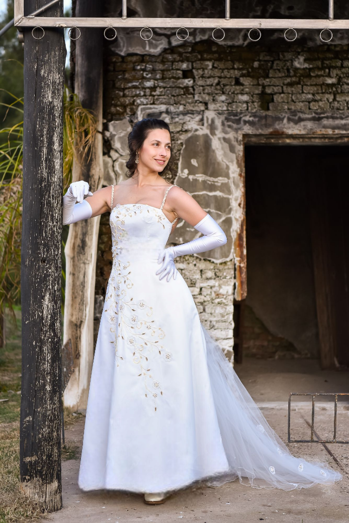 Una mujer con un vestido de novia está parada frente a un edificio de ladrillos.