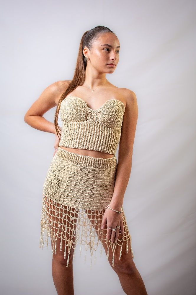 Una mujer con un vestido dorado está de pie con las manos en las caderas.