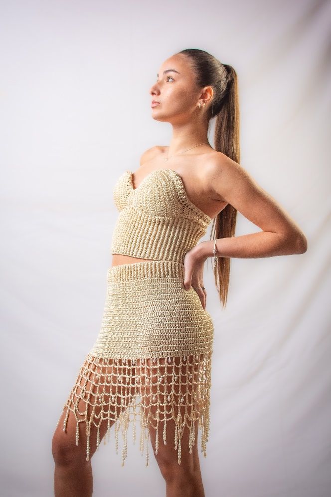 Una mujer con un vestido dorado está de pie con las manos en las caderas.
