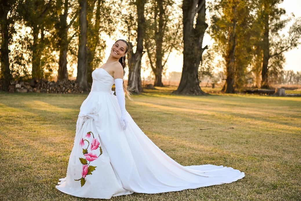 Una mujer con un vestido de novia está parada en la hierba.