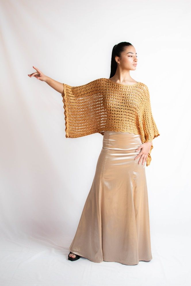 Una mujer lleva un top de crochet y una falda dorada.