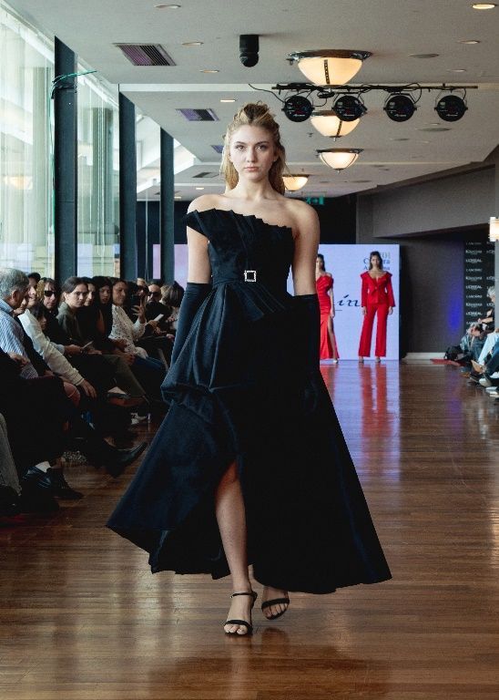 Una mujer con un vestido azul camina por la pasarela en un desfile de moda.