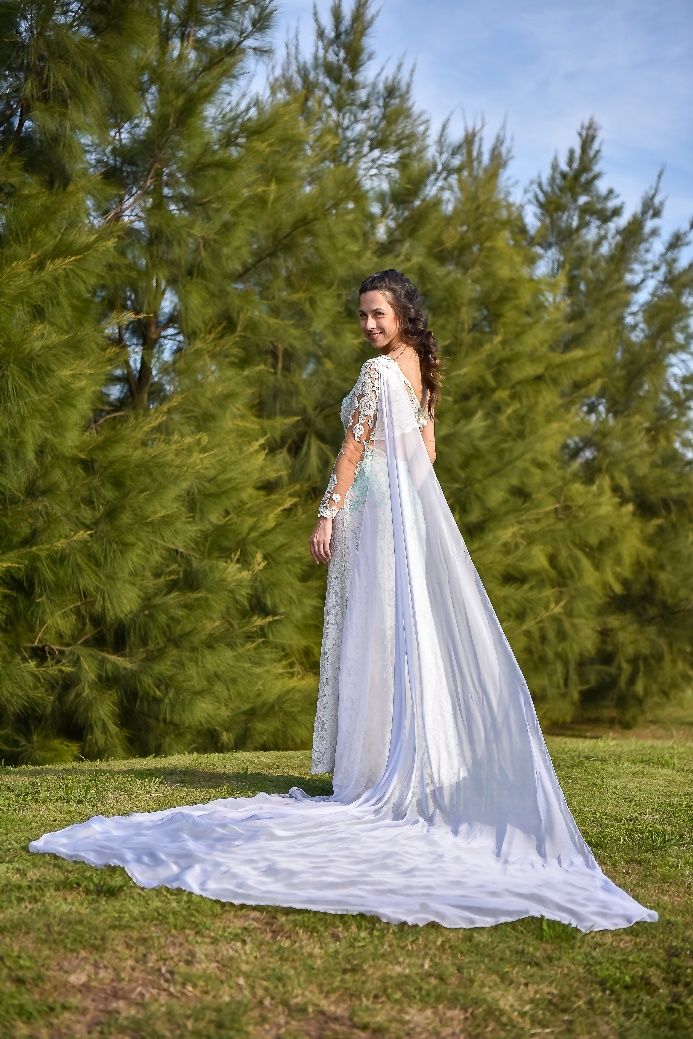 Una mujer con un vestido de novia blanco está parada en la hierba.