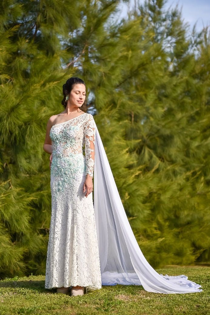 Una mujer con un vestido de novia blanco está parada en la hierba.