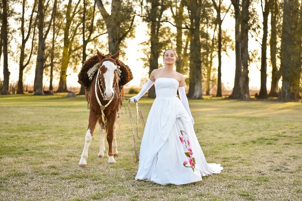 Una mujer con un vestido de novia está parada en la hierba.