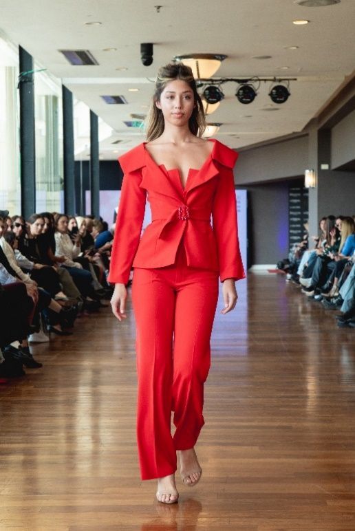 Una modelo camina por la pasarela en un desfile de moda con un vestido de lentejuelas azules y verdes.