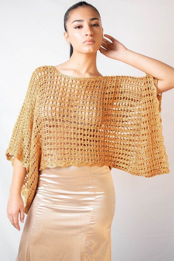 Una mujer lleva un top de crochet y una falda dorada.