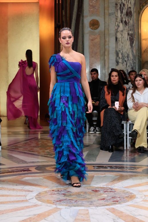 Una mujer con un vestido azul está parada en un conjunto de escaleras.