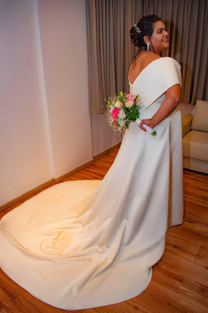 La novia lleva un vestido de novia blanco y sostiene un ramo de flores.