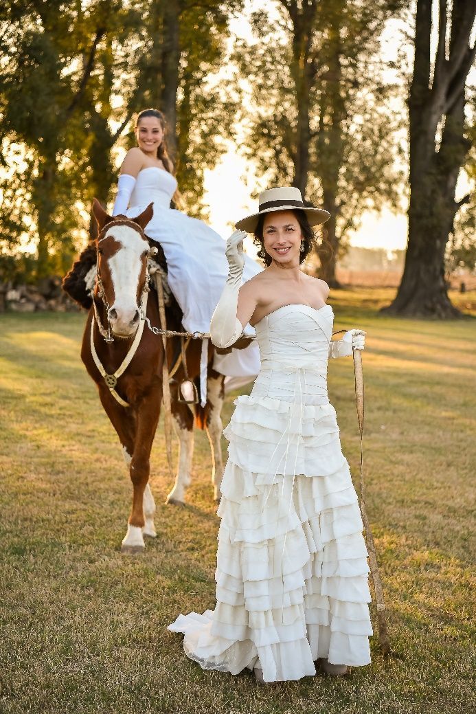 Una mujer con un vestido blanco está de pie junto a un caballo.