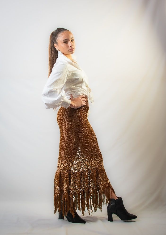 torso de mujer de perfil con blusa blanca y pollera marron tejida en crochet