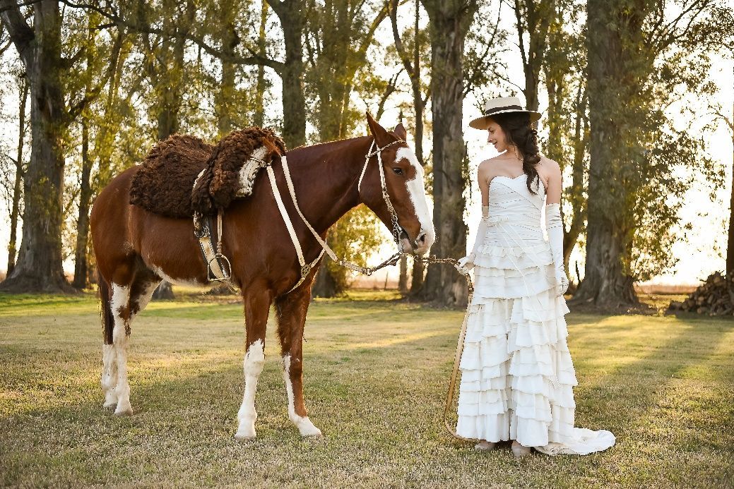 Una mujer con un vestido blanco está de pie junto a un caballo.