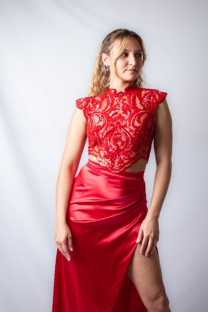 Una mujer con un vestido rojo está parada frente a una pared blanca.