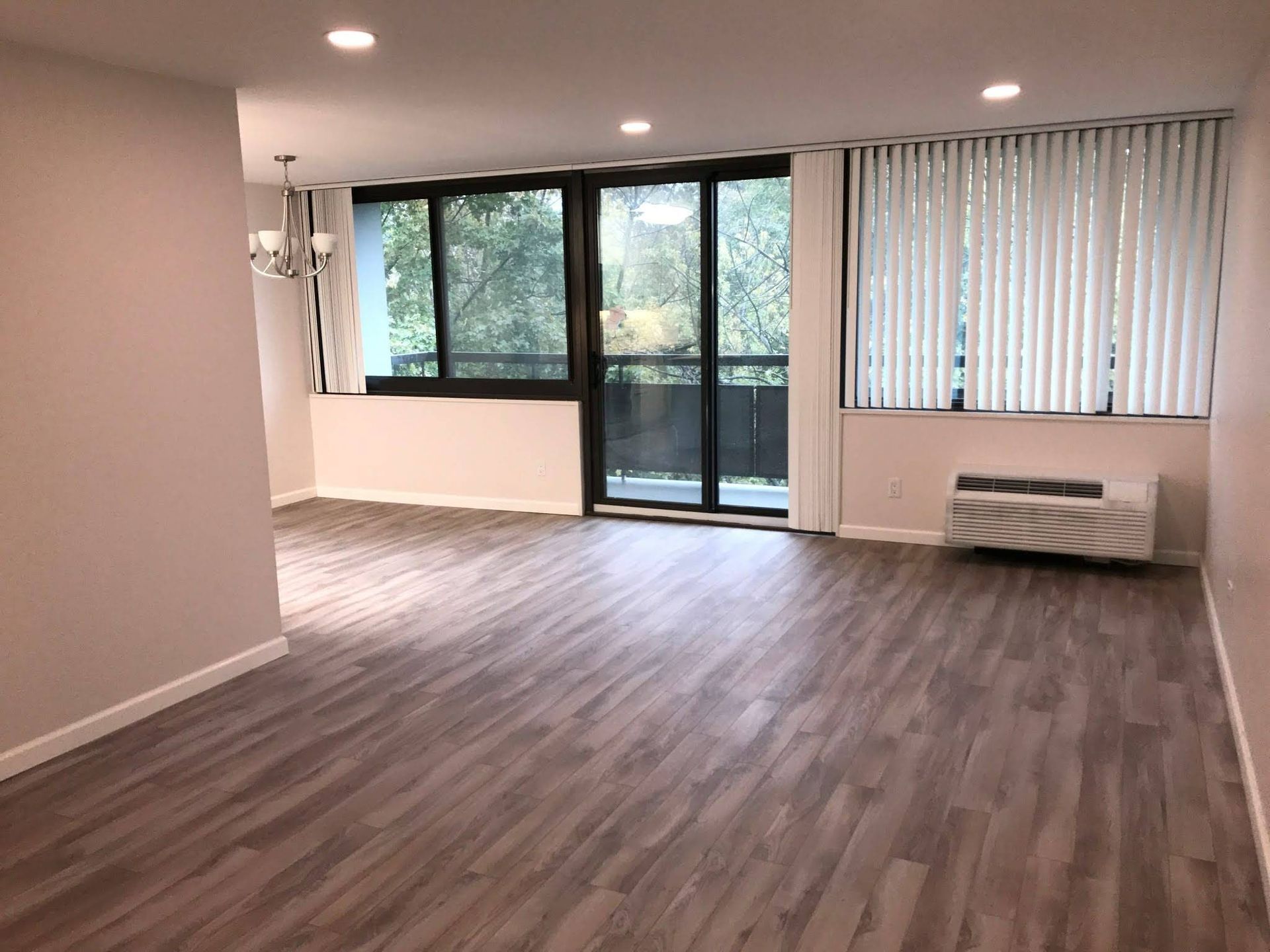 An empty living room with hardwood floors and sliding glass doors