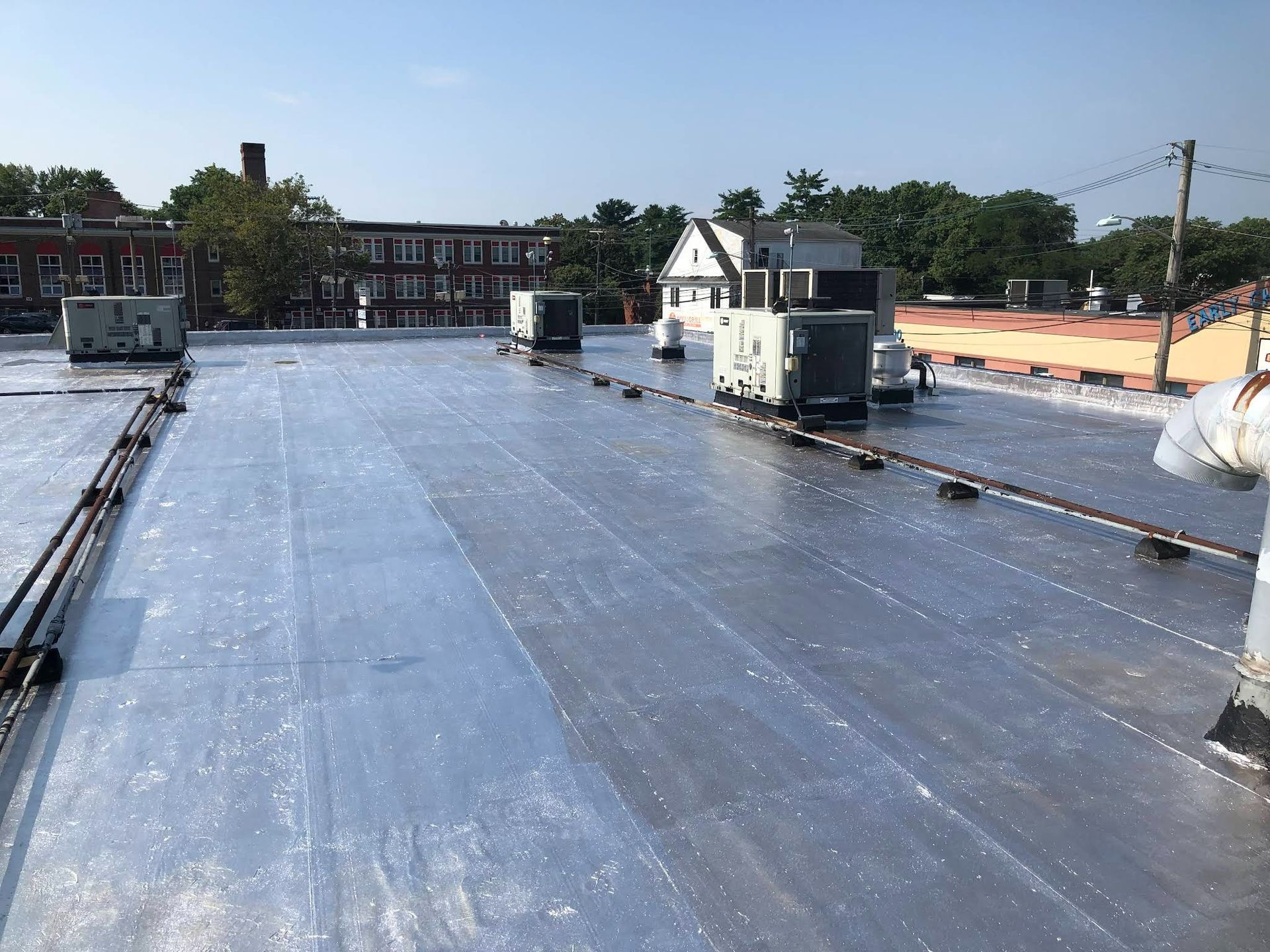A roof with a lot of pipes on it and a building in the background.