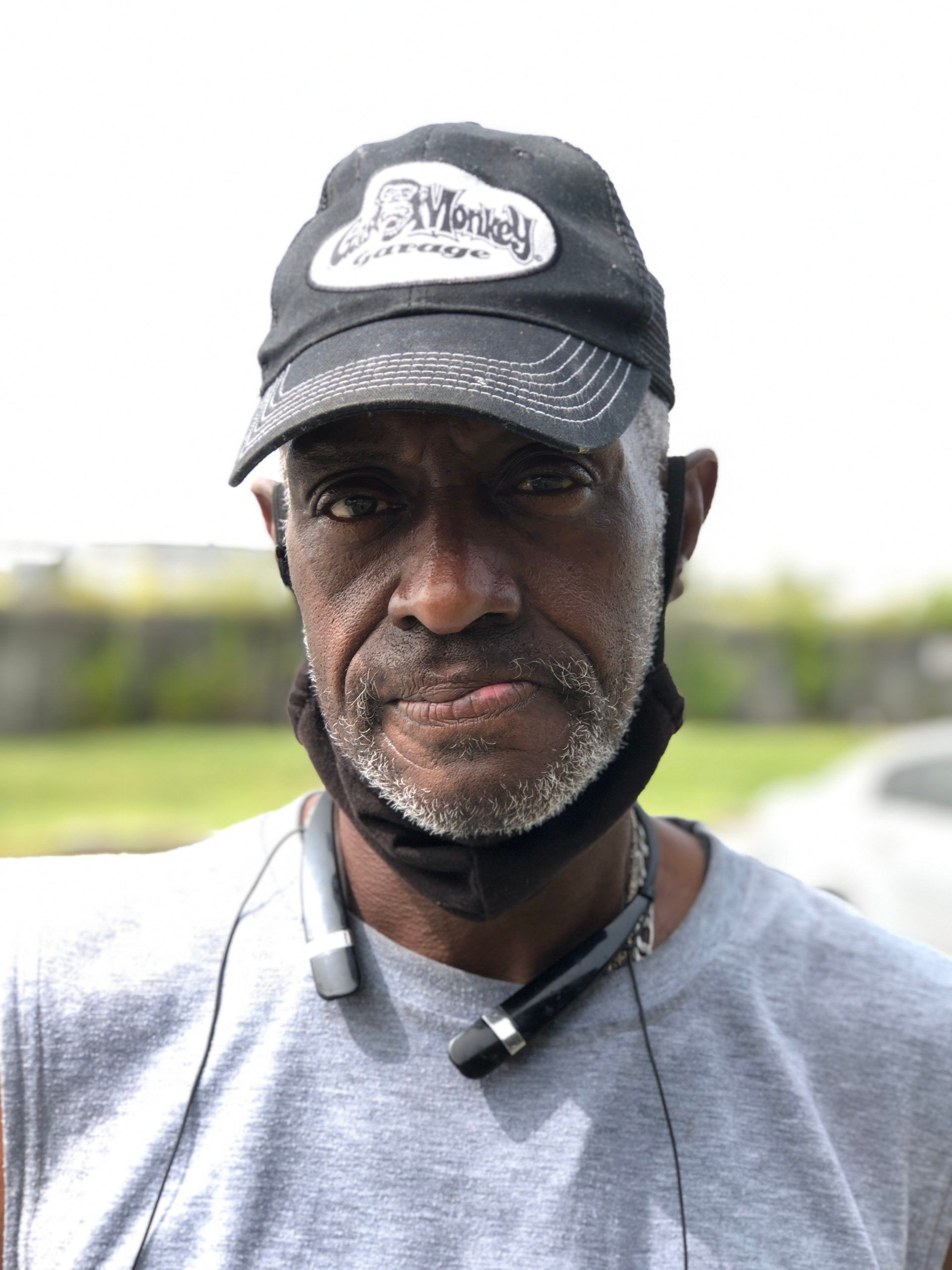 Man wearing a cap and mask, outdoors. Light skin, short hair, looking at the camera.