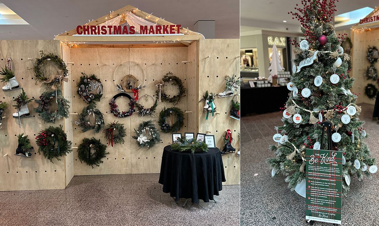 Christmas market display with wreaths, a decorated tree, and small table.