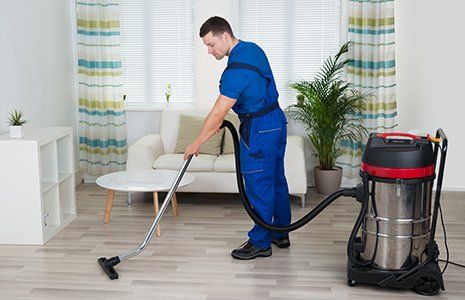 Male worker cleaning floor with vacuum cleaner
