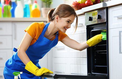 Woman washes an oven in the kitchen