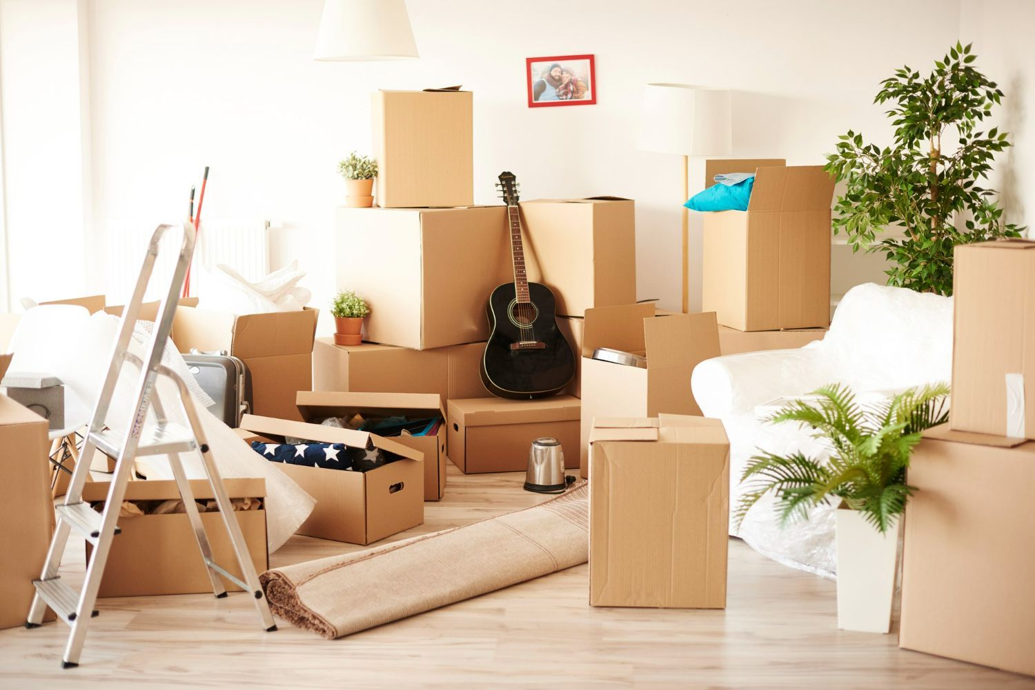 A living room filled with cardboard boxes and a guitar.