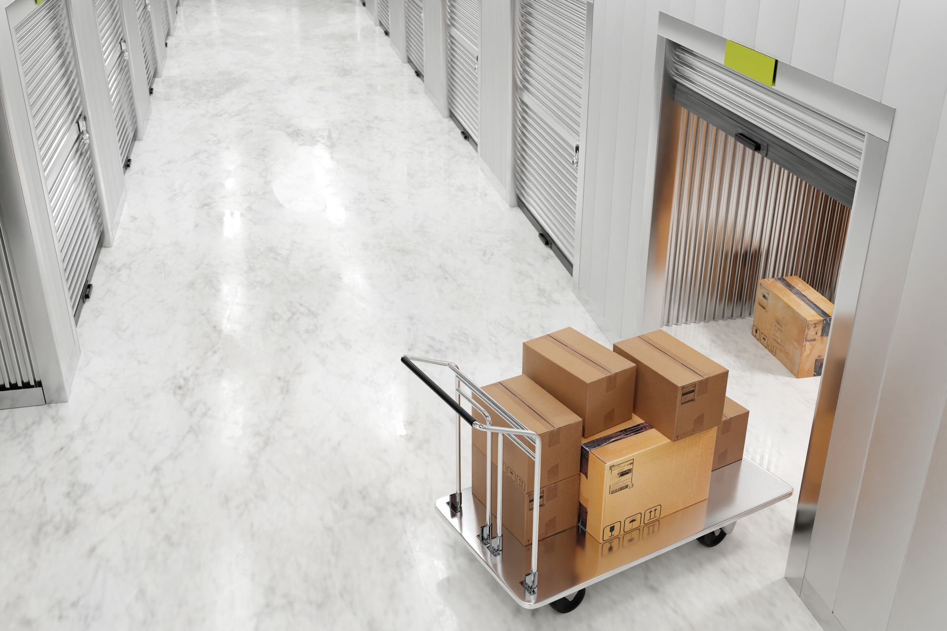 Cart loaded with boxes in storage unit hallway, near an open elevator.
