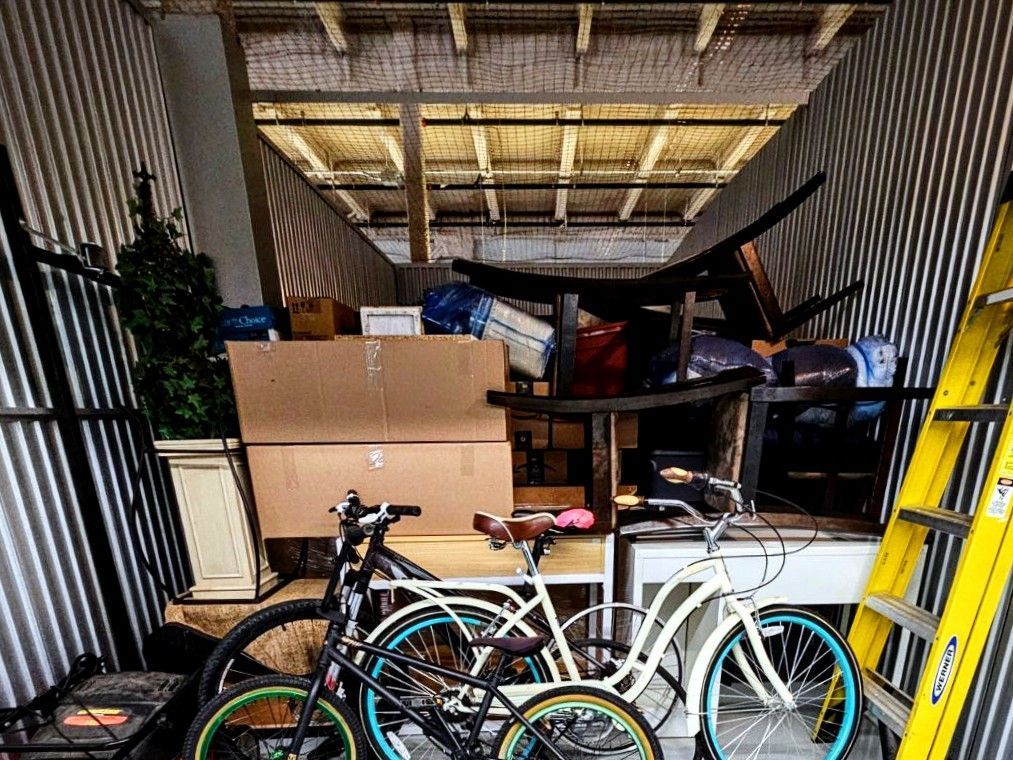 A storage shed filled with lots of furniture and bicycles.