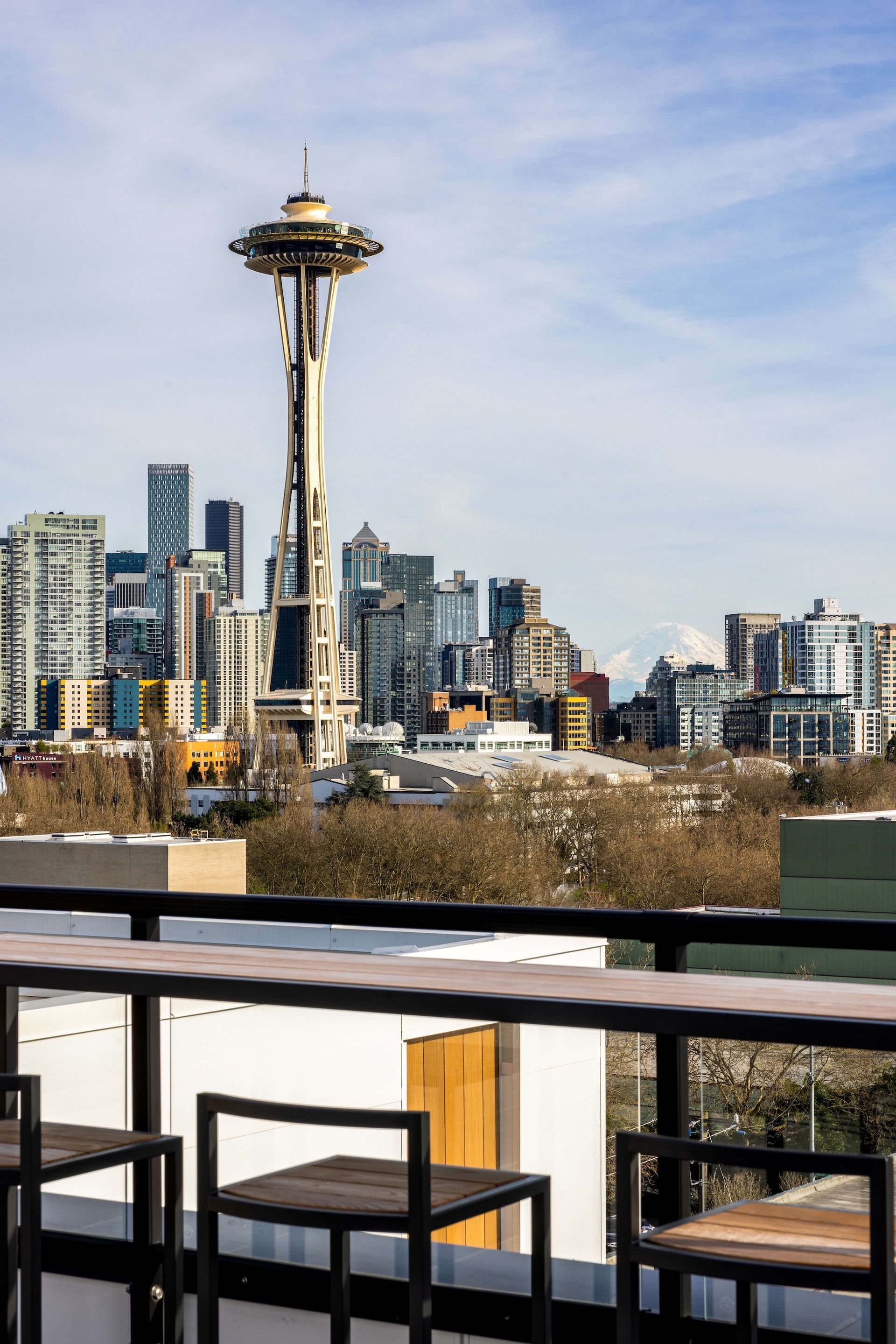 Space Needle and Seattle skyline viewed from a rooftop with chairs.