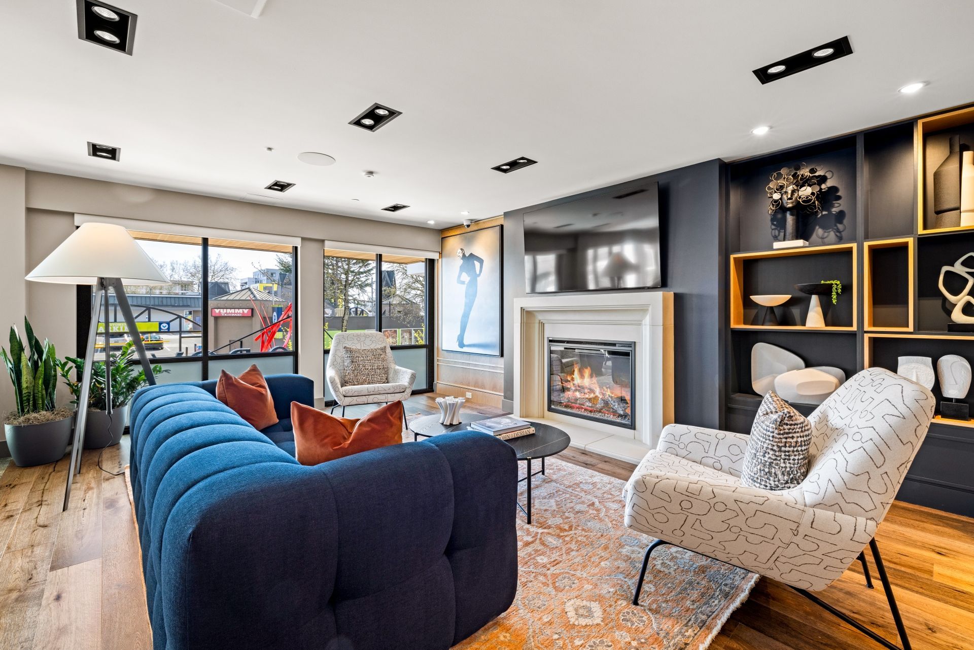A living room with a blue couch , white chairs , and a fireplace.