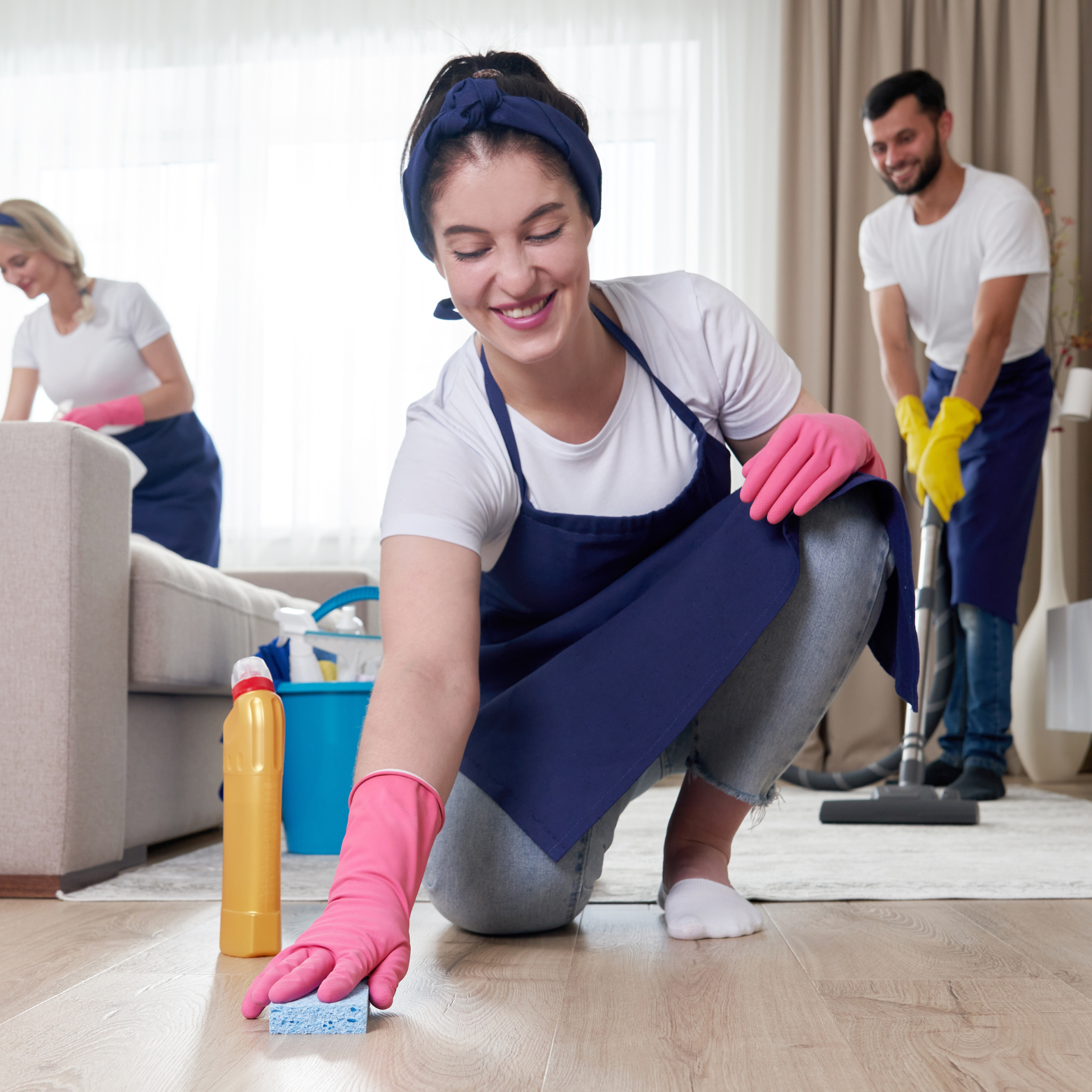 A woman wearing pink gloves is cleaning the floor in a living room
