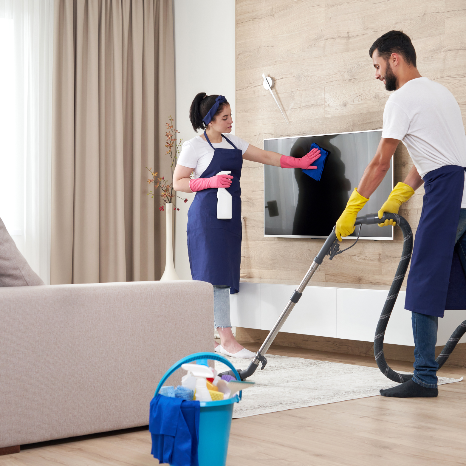 A man and a woman are cleaning a living room with a vacuum cleaner.