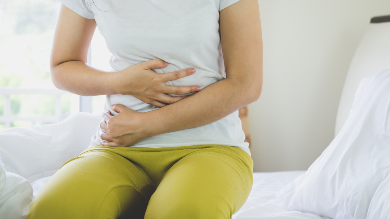 A graphic of a woman cluching her stomach on a white bed