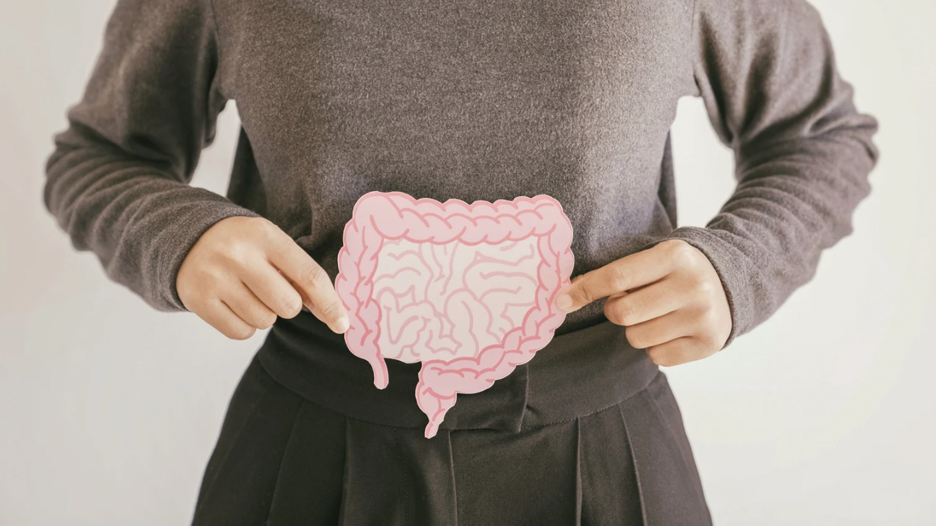 A woman is holding a paper cut out of her stomach.