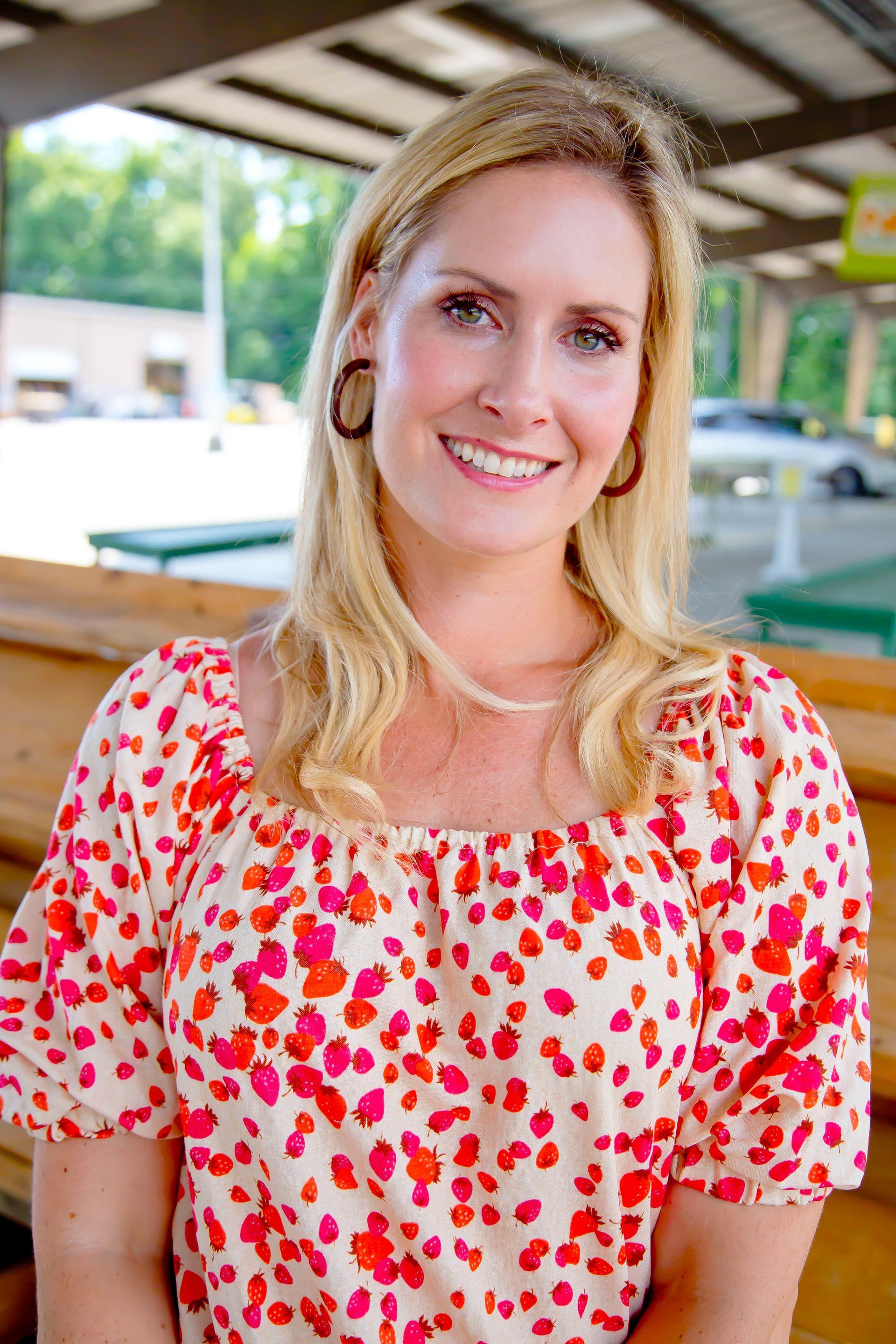 A woman in a pink and white polka dot top is smiling for the camera.