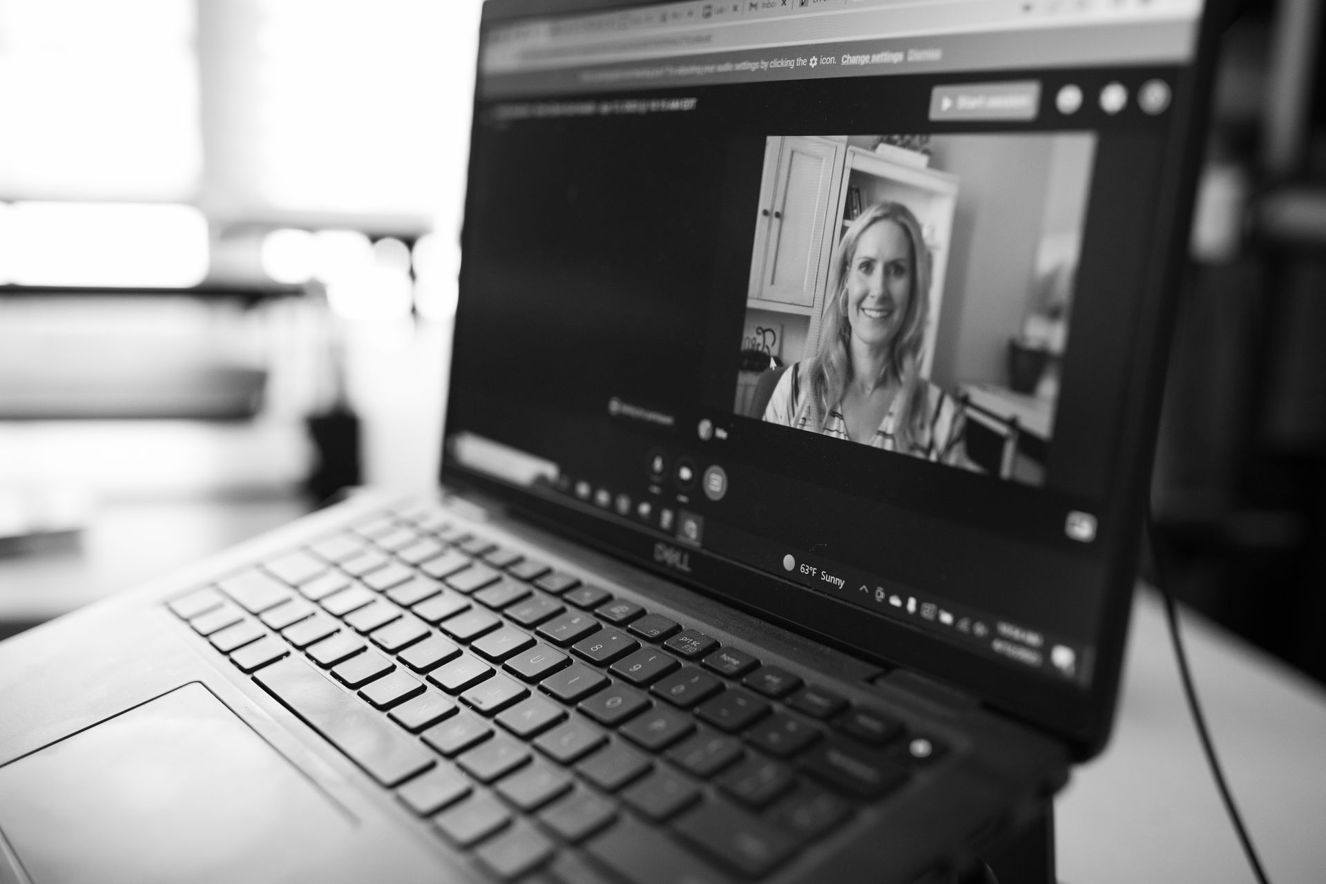 A black and white photo of a laptop with a woman on the screen.