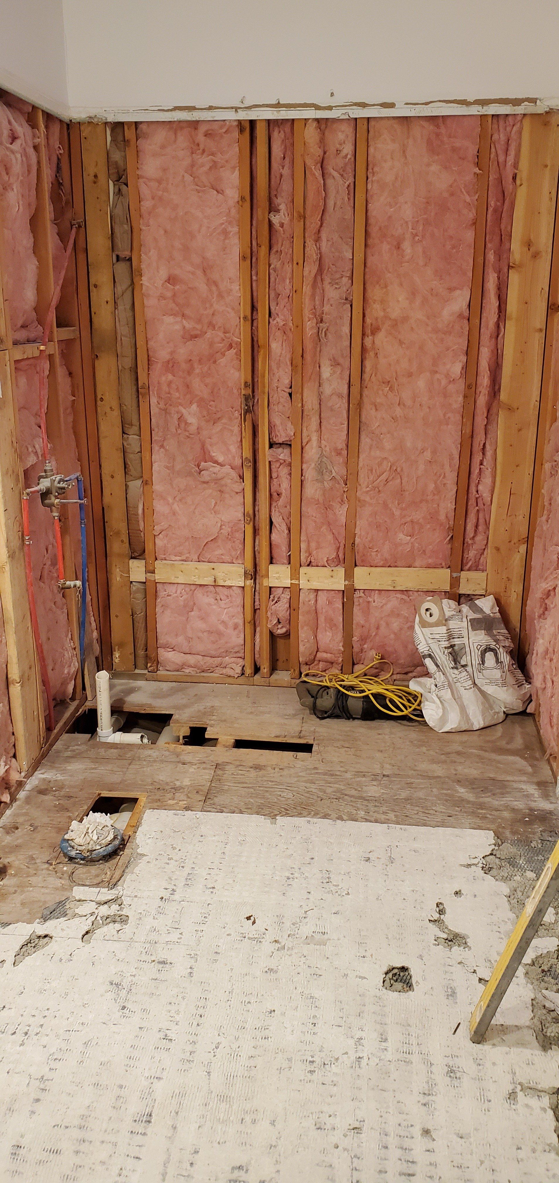 a bathroom under construction with pink insulation on the walls and floor .