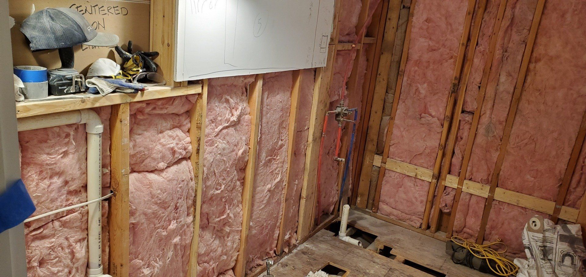 a bathroom under construction with pink insulation on the walls and floor .