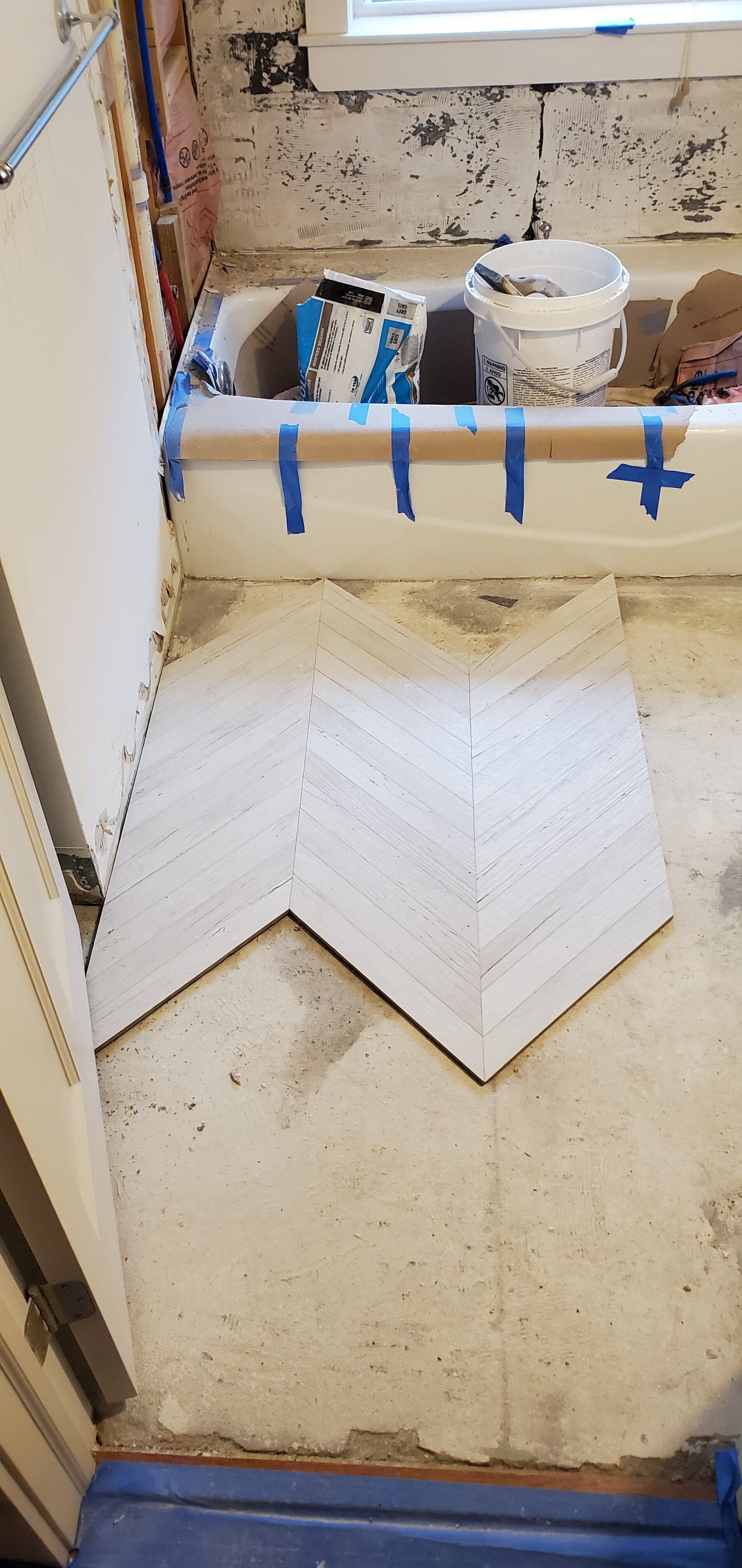 a bathroom with a bathtub and a tile floor being installed .