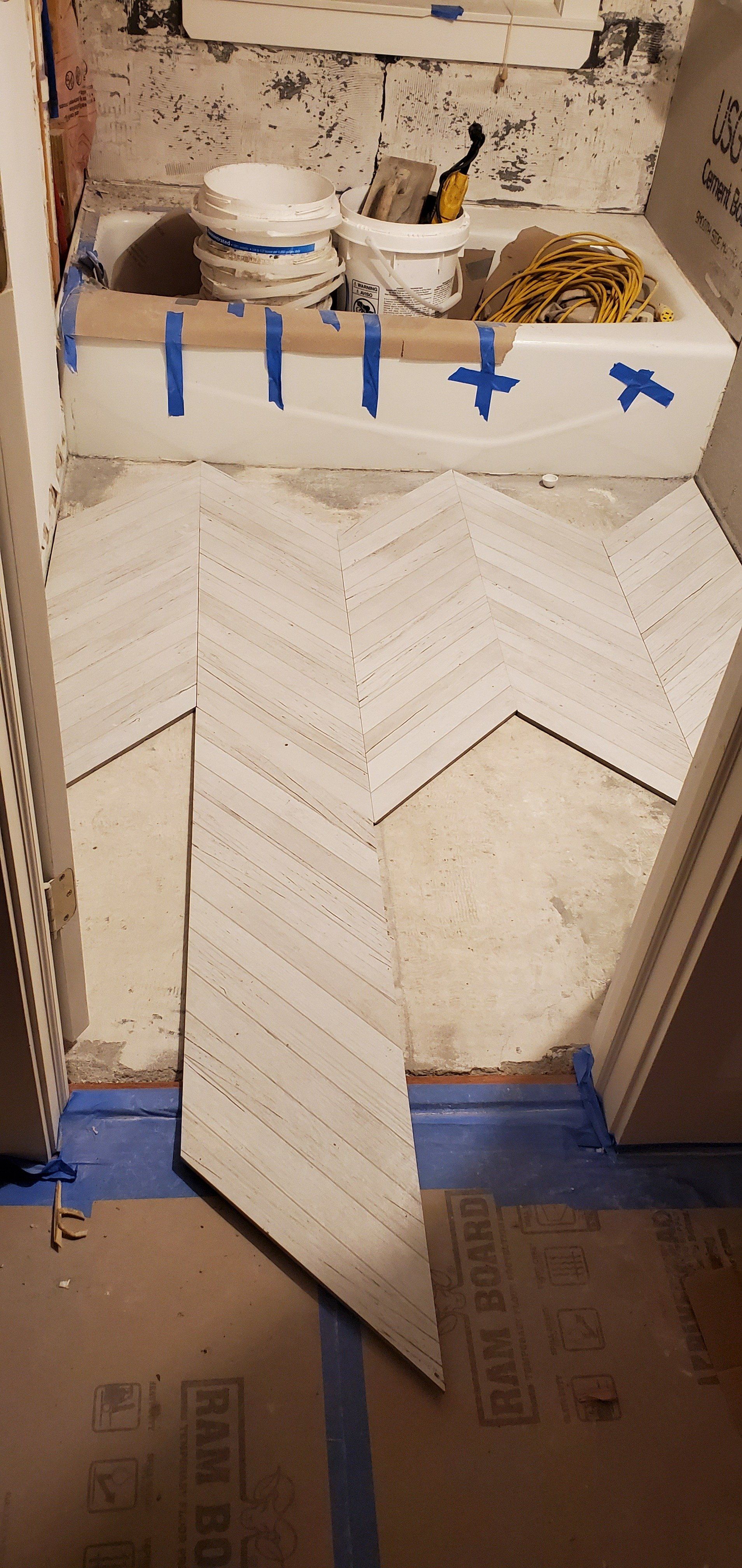 a bathroom is being remodeled with a herringbone tile floor .
