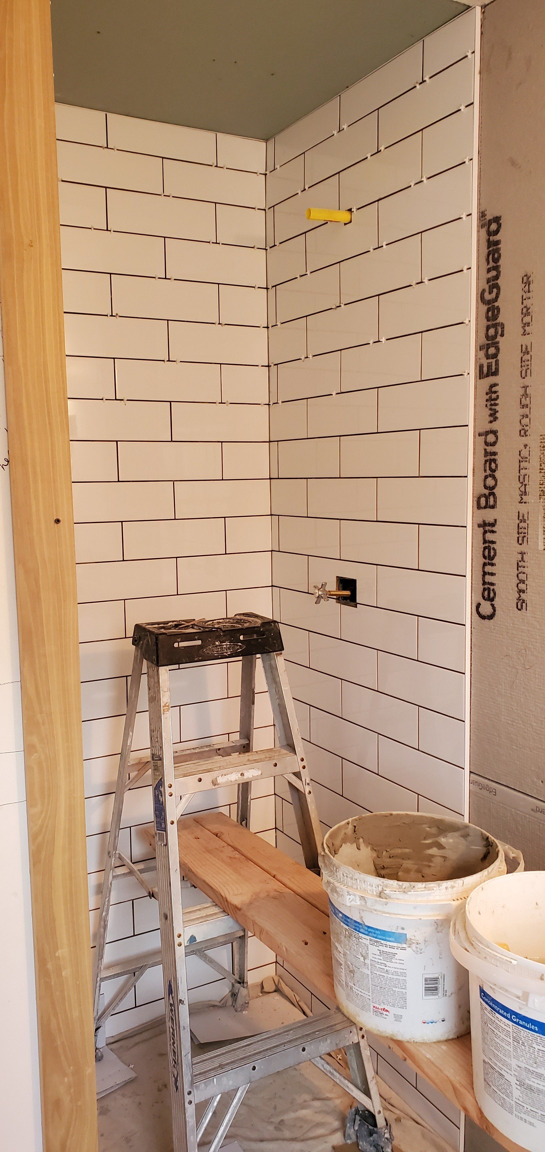 a bathroom under construction with a ladder and buckets of paint .