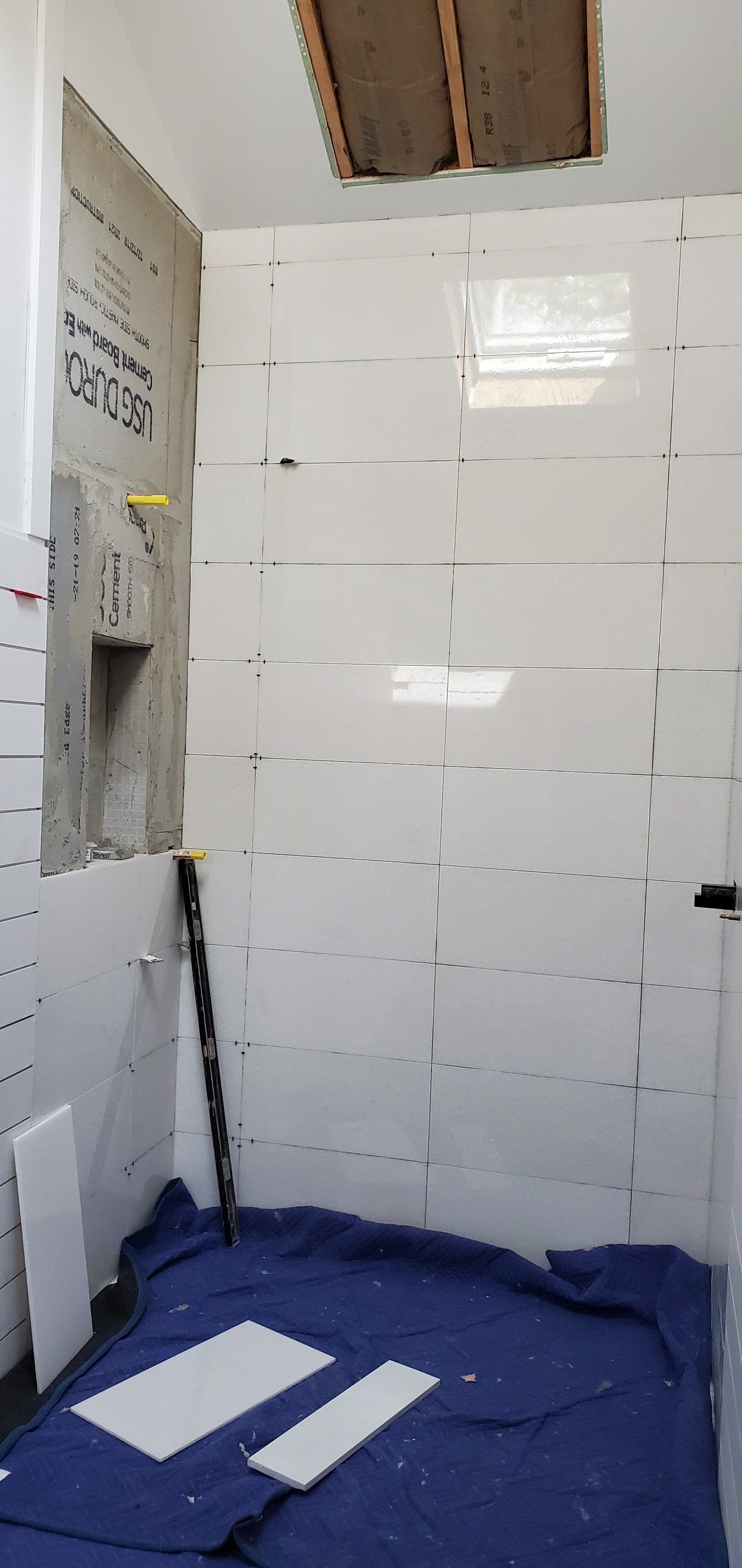 a bathroom under construction with white tiles and a blue rug on the floor .