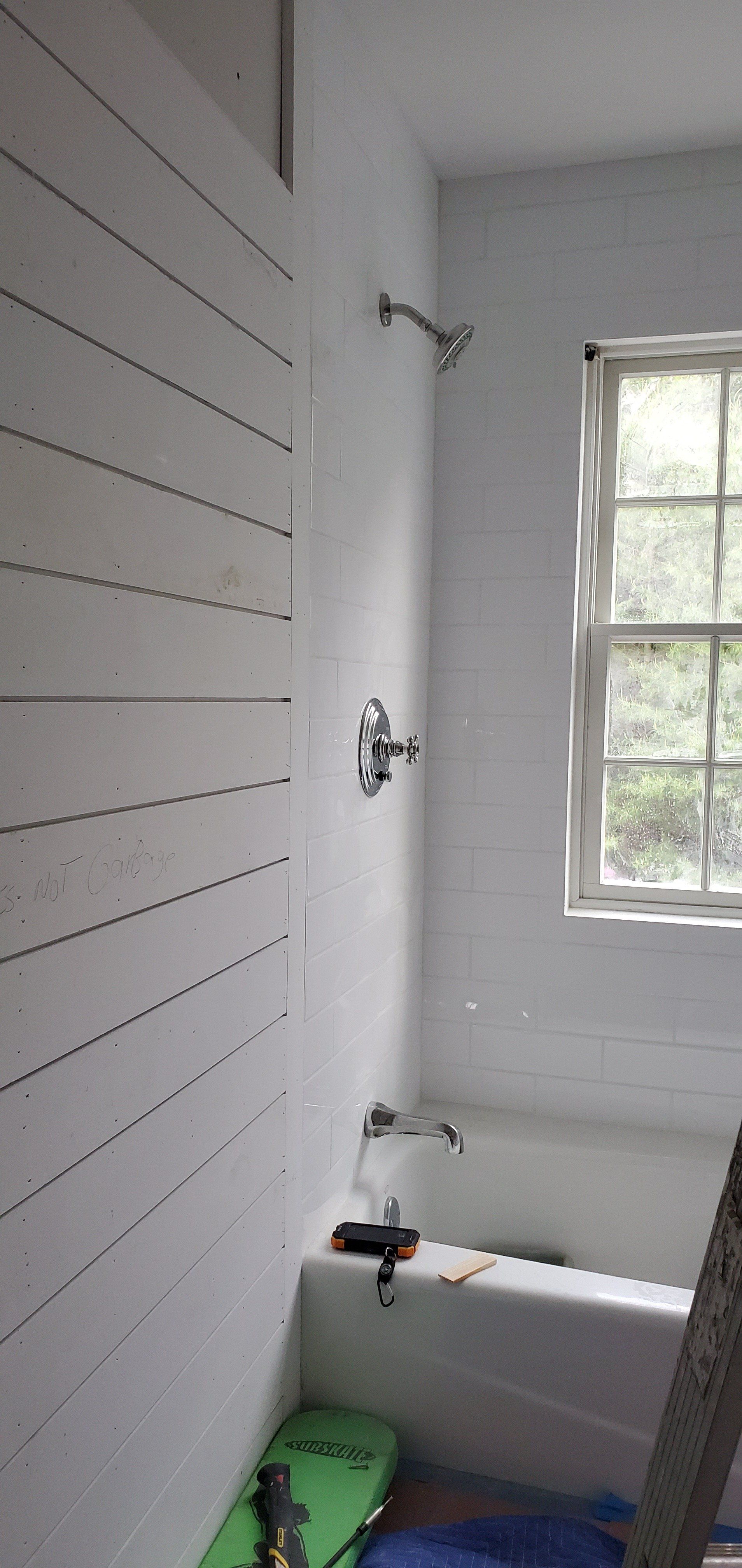 a bathroom with a bathtub , shower , and window .