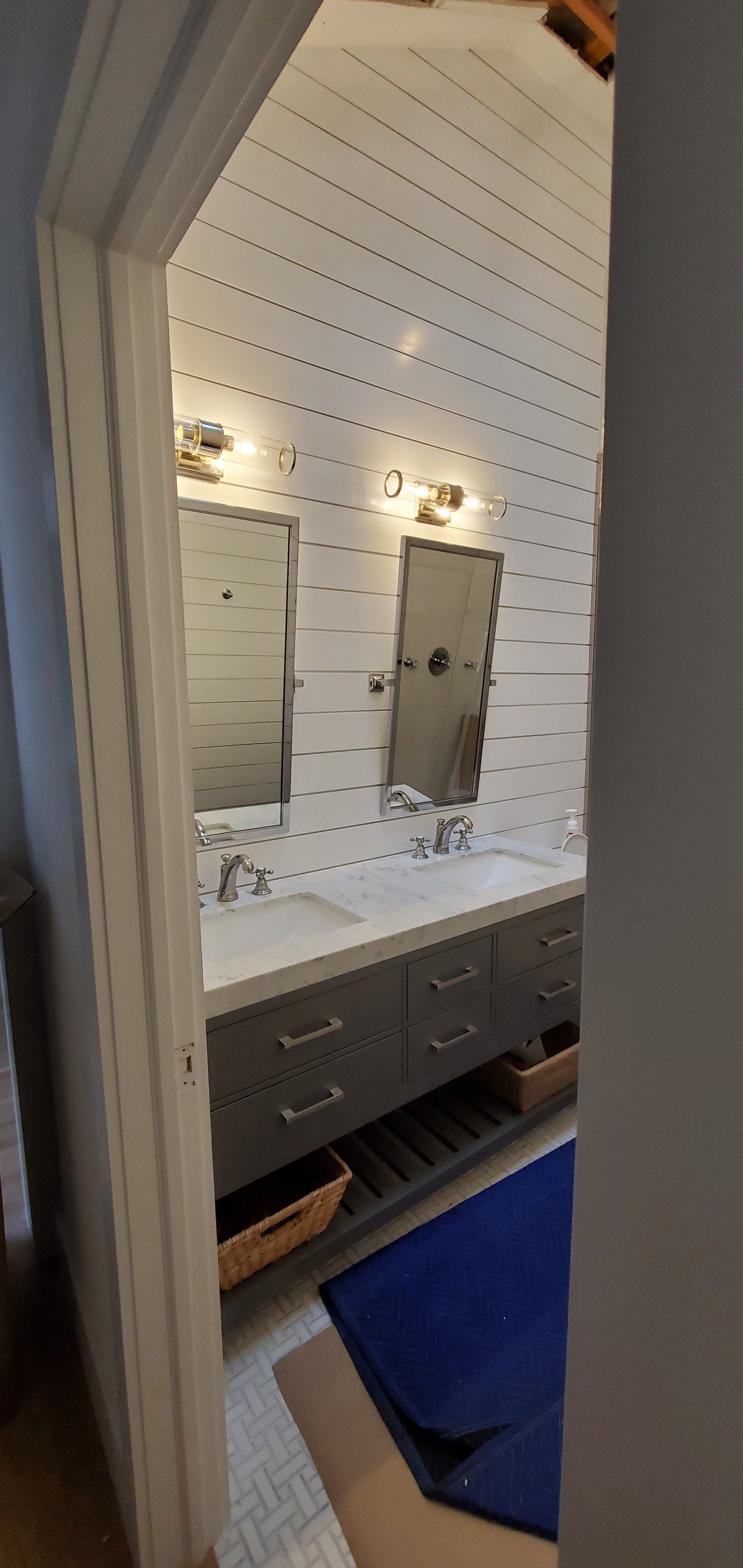 a bathroom with two sinks , two mirrors and a blue rug