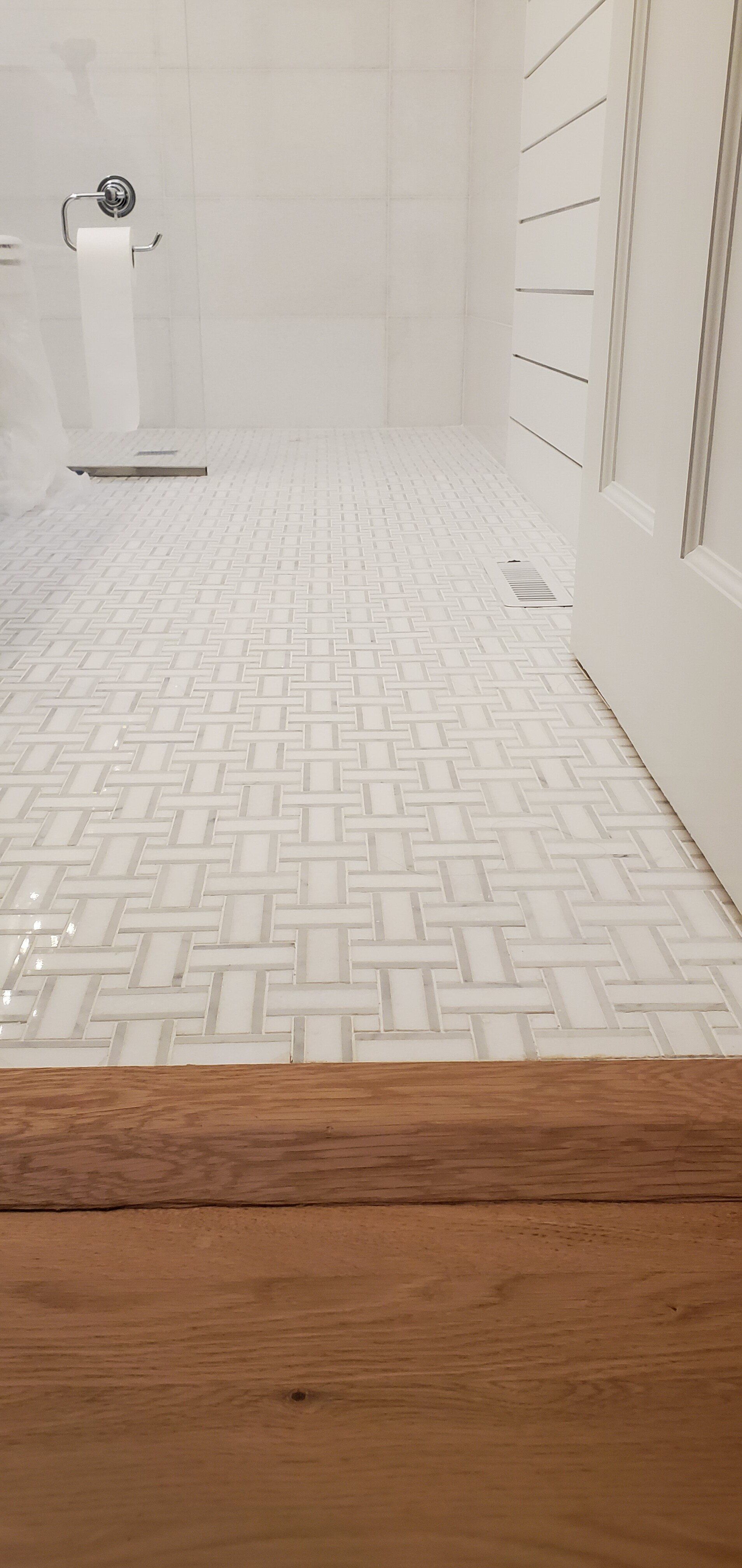 a bathroom with white tiles and a wooden floor .
