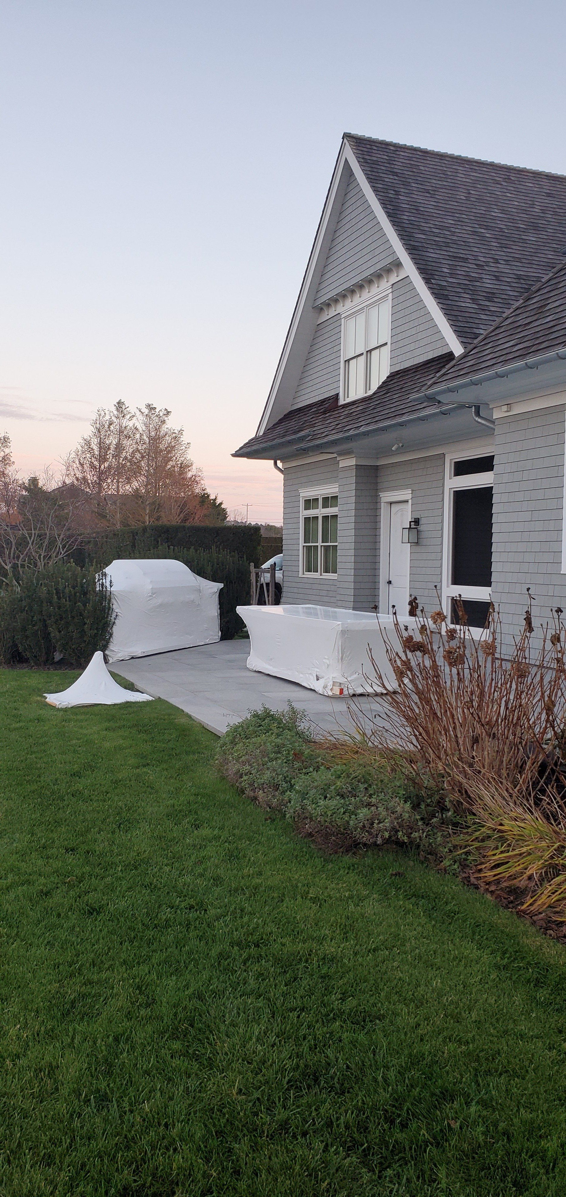 a house with benches covered in white shrink wraps in front of it