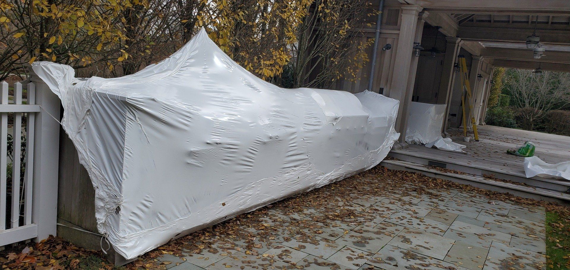 a large equipment wrapped in white shrink wrap in a backyard.